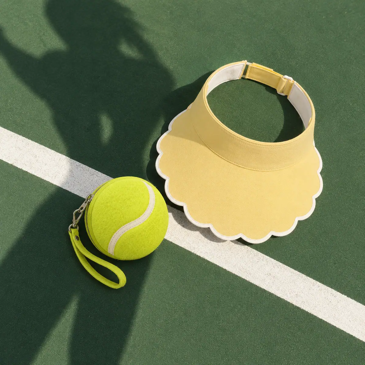 A lime round pouch and a butter visor on the white line of a green court