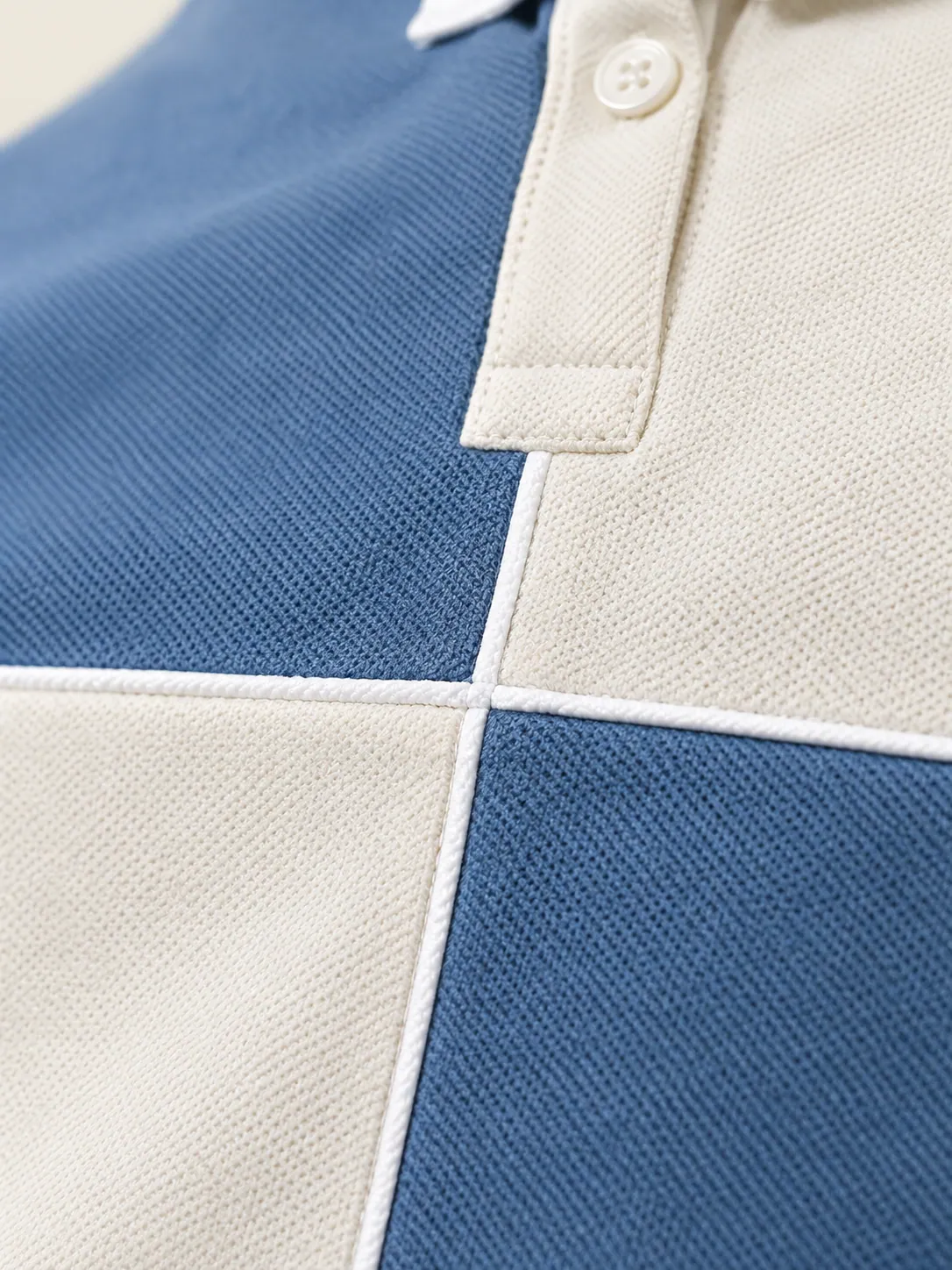 Service Box Colourblock Polo, close-up of the crossing piped seams where the four panels meet