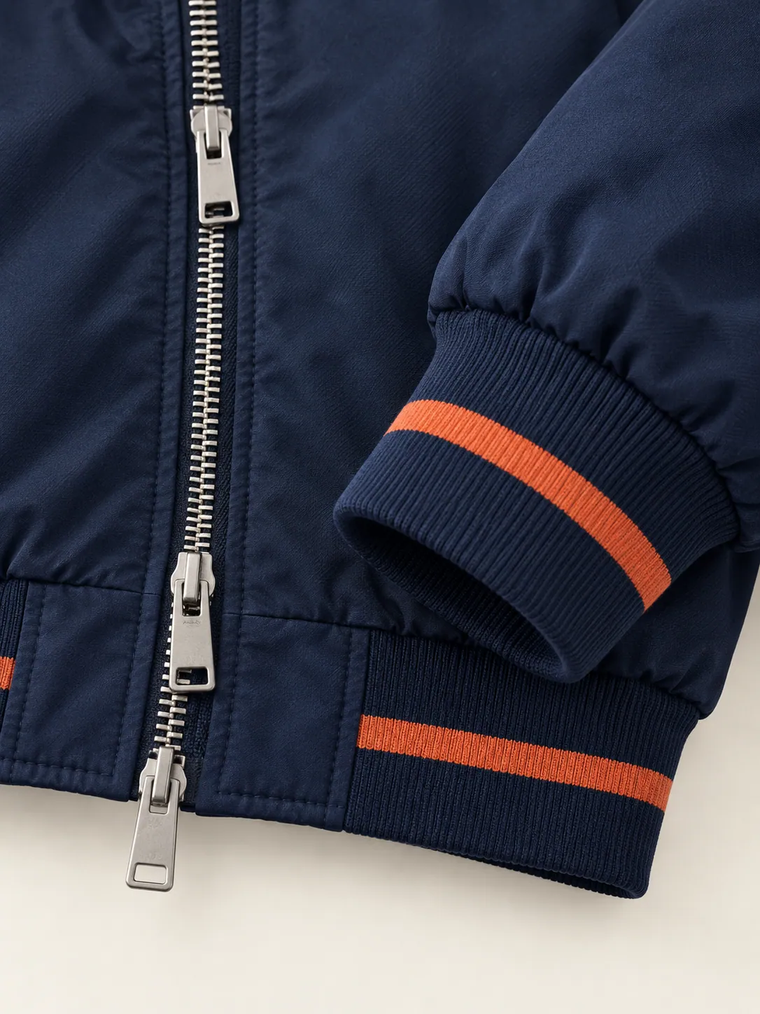 Two-Way Zip Bomber, close-up of the two-way zip pulls and clay-striped rib cuff